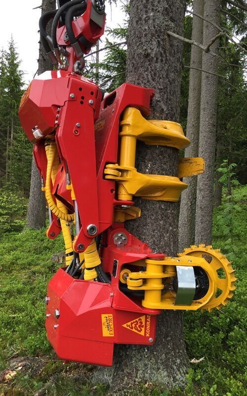 Red and yellow forestry machine felling a tree