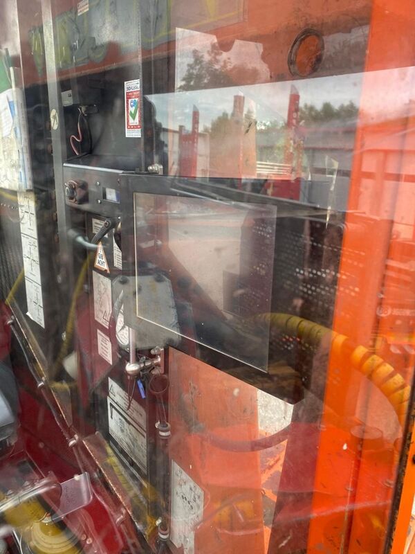 The control panel inside an industrial machine featuring various gauges and a digital screen.