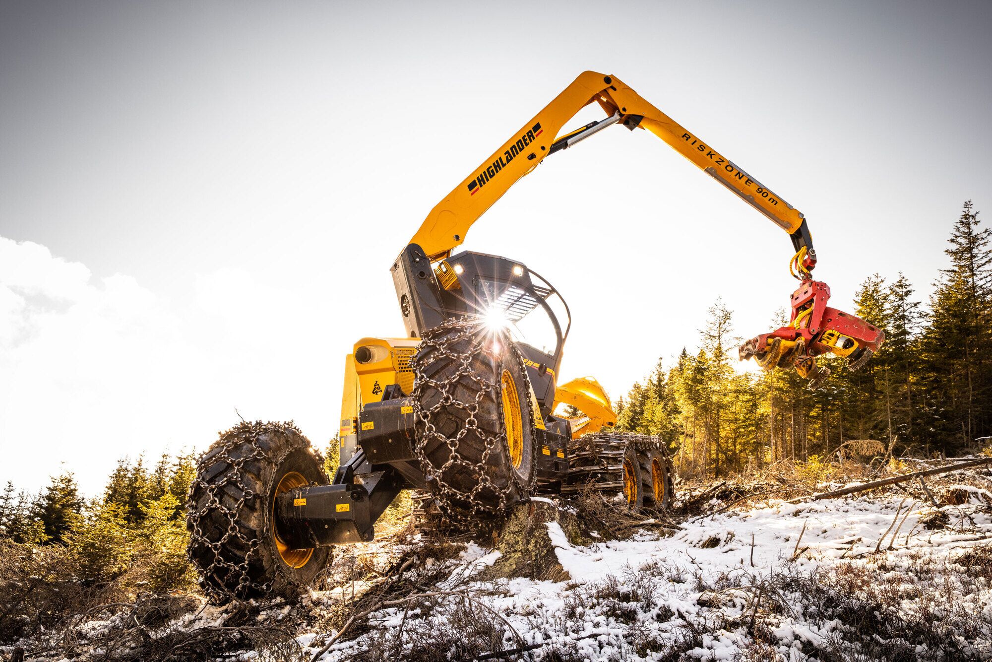 A dynamic harvester machine working in a snowy forest landscape