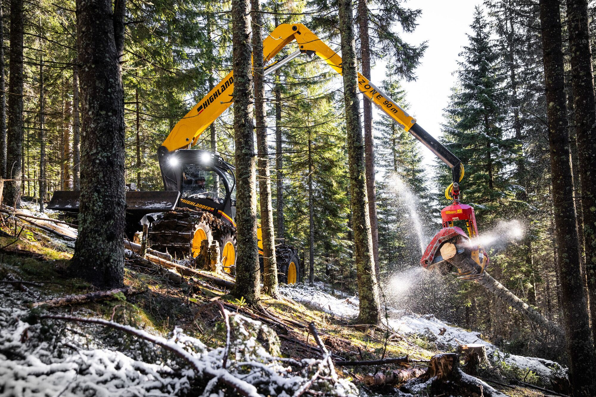 Forestry machine with yellow arm operating in a snowy forest