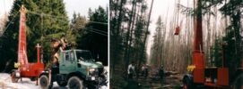 A logging truck equipped with a hoist lifting logs in a forest setting