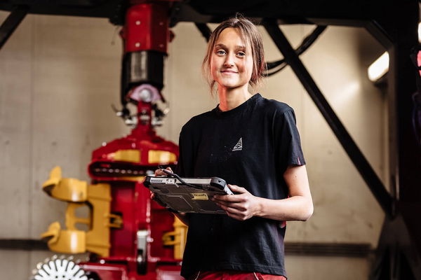 Eine junge Frau hält ein Gerät vor Baumaschinen
