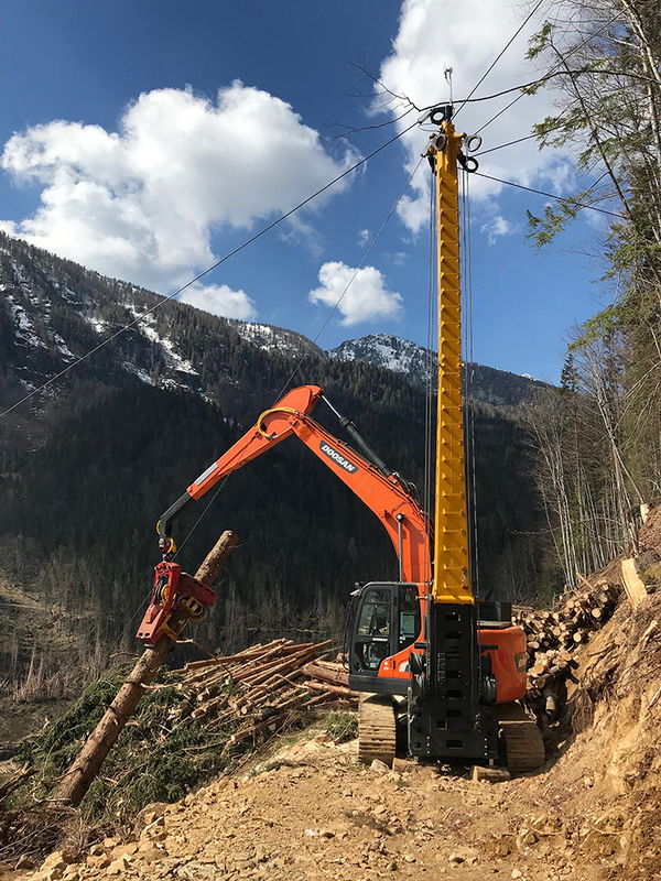 Heavy equipment excavator with logging attachments on a mountain slope